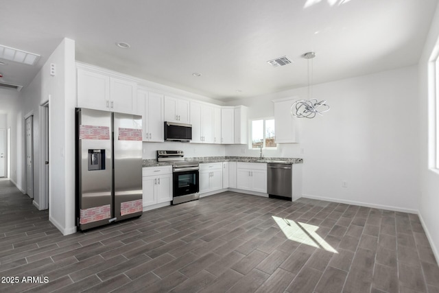 kitchen with appliances with stainless steel finishes, light stone counters, hanging light fixtures, wood tiled floor, and white cabinetry