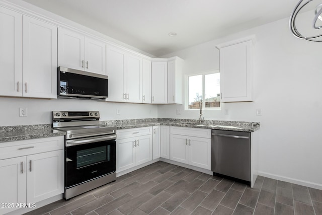 kitchen featuring light stone counters, appliances with stainless steel finishes, wood tiled floor, white cabinets, and a sink