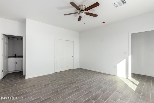 unfurnished bedroom featuring baseboards, visible vents, a ceiling fan, ensuite bath, and a sink