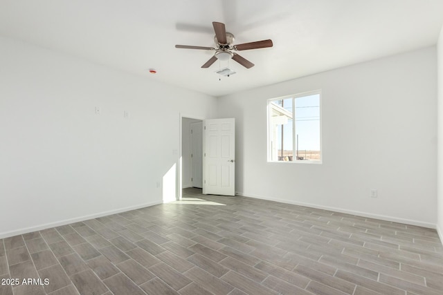 spare room featuring a ceiling fan, visible vents, baseboards, and wood finished floors