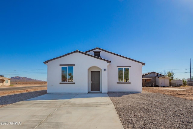 view of front facade with a patio area, a tile roof, a mountain view, and stucco siding