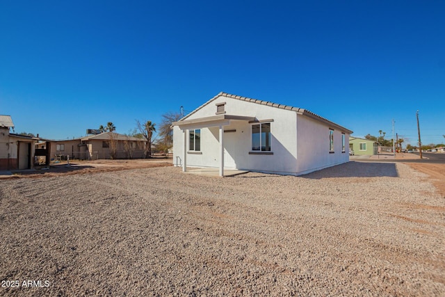 rear view of property with a tiled roof, a residential view, and stucco siding