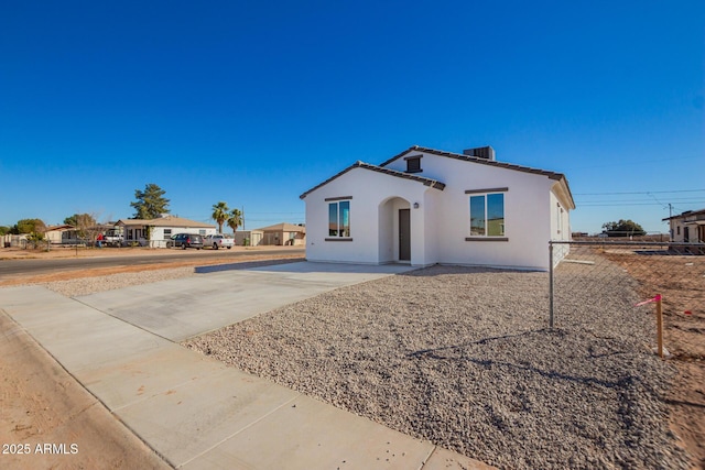 view of front of house featuring central AC, fence, a tile roof, concrete driveway, and stucco siding