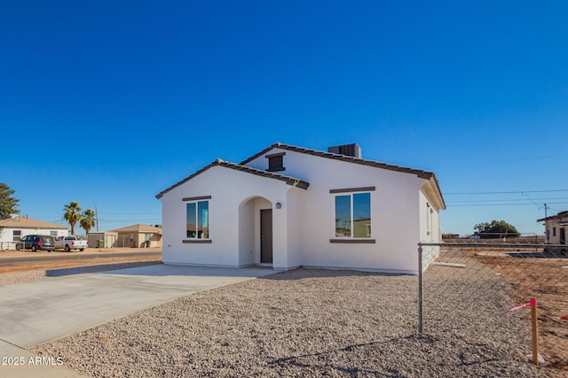 mediterranean / spanish home featuring a tile roof, fence, and stucco siding