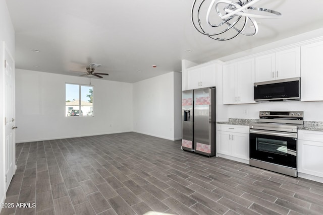 kitchen with light stone countertops, appliances with stainless steel finishes, open floor plan, white cabinets, and wood finished floors