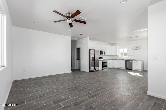 unfurnished living room featuring visible vents, a ceiling fan, and baseboards