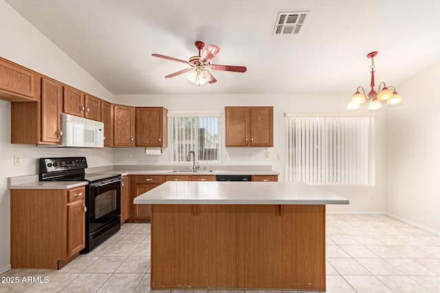 kitchen featuring white microwave, visible vents, black range with electric stovetop, brown cabinetry, and a sink