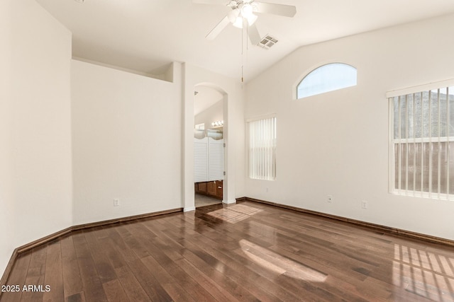 empty room featuring visible vents, baseboards, vaulted ceiling, wood finished floors, and a ceiling fan