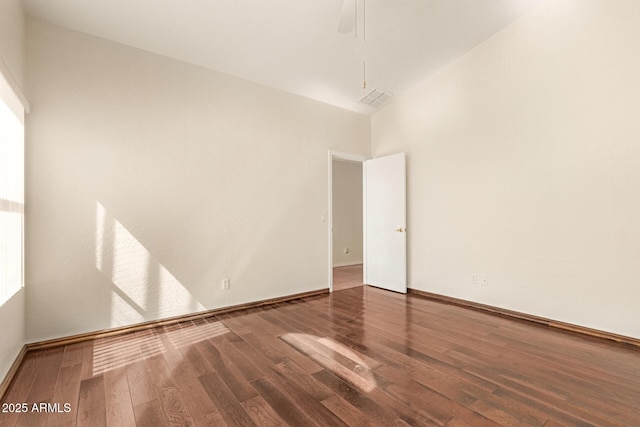 empty room featuring wood finished floors, visible vents, and baseboards