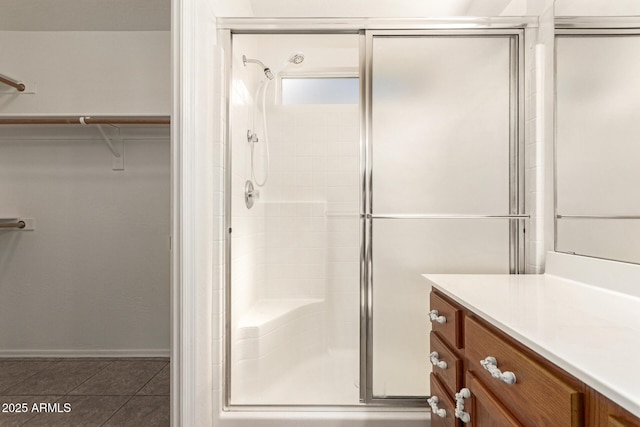 bathroom with a spacious closet, tile patterned floors, a stall shower, and vanity