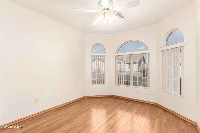 spare room with hardwood / wood-style flooring, baseboards, visible vents, and ceiling fan