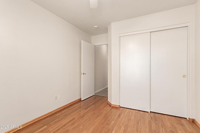 unfurnished bedroom featuring light wood finished floors, ceiling fan, and a closet