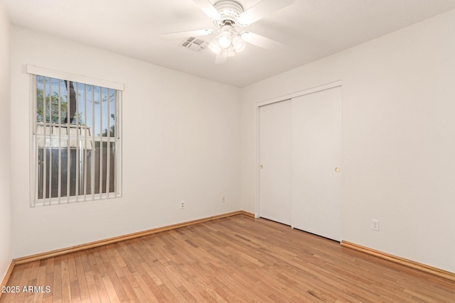 unfurnished bedroom featuring baseboards, visible vents, light wood finished floors, ceiling fan, and a closet