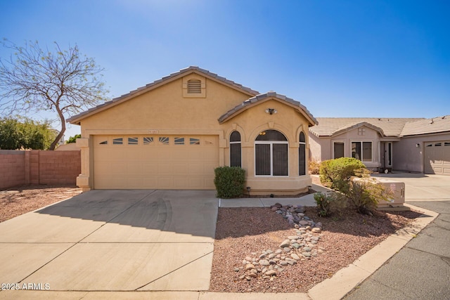 mediterranean / spanish home with a tiled roof, an attached garage, driveway, and stucco siding