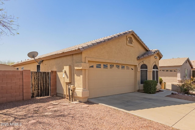 view of front of home featuring stucco siding, driveway, fence, an attached garage, and a tiled roof