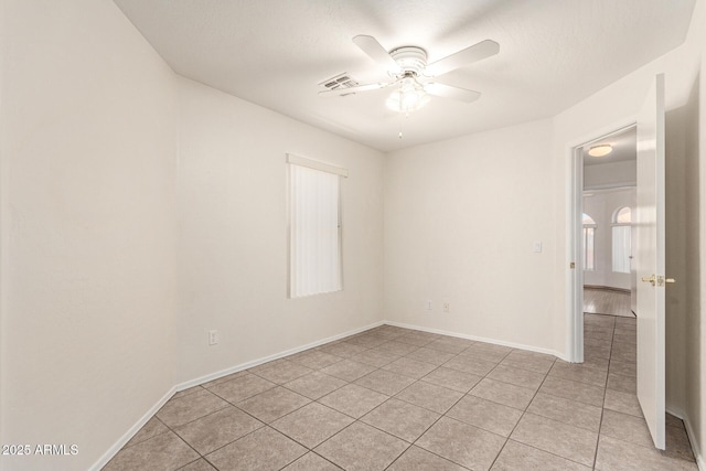 empty room featuring visible vents, baseboards, light tile patterned flooring, and a ceiling fan