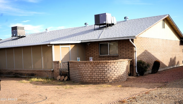 rear view of house featuring central air condition unit and a sunroom