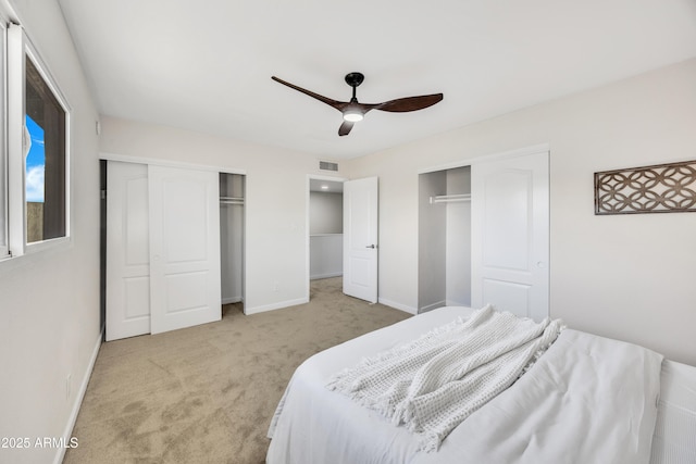 bedroom featuring visible vents, two closets, baseboards, carpet flooring, and a ceiling fan