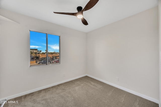 carpeted spare room featuring baseboards and ceiling fan