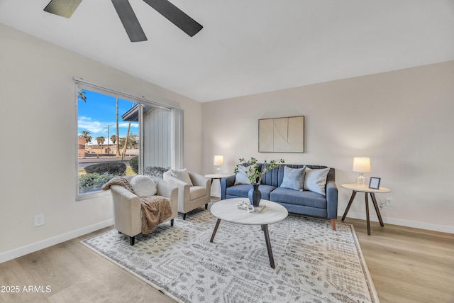 living area featuring a ceiling fan, light wood-type flooring, and baseboards