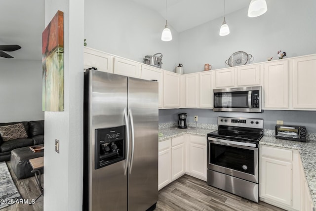 kitchen with high vaulted ceiling, decorative light fixtures, white cabinets, light stone counters, and stainless steel appliances