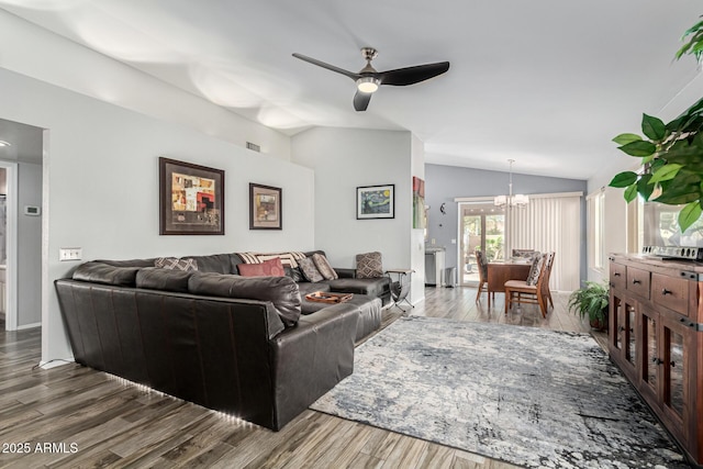 living room with dark wood-type flooring, ceiling fan with notable chandelier, and vaulted ceiling