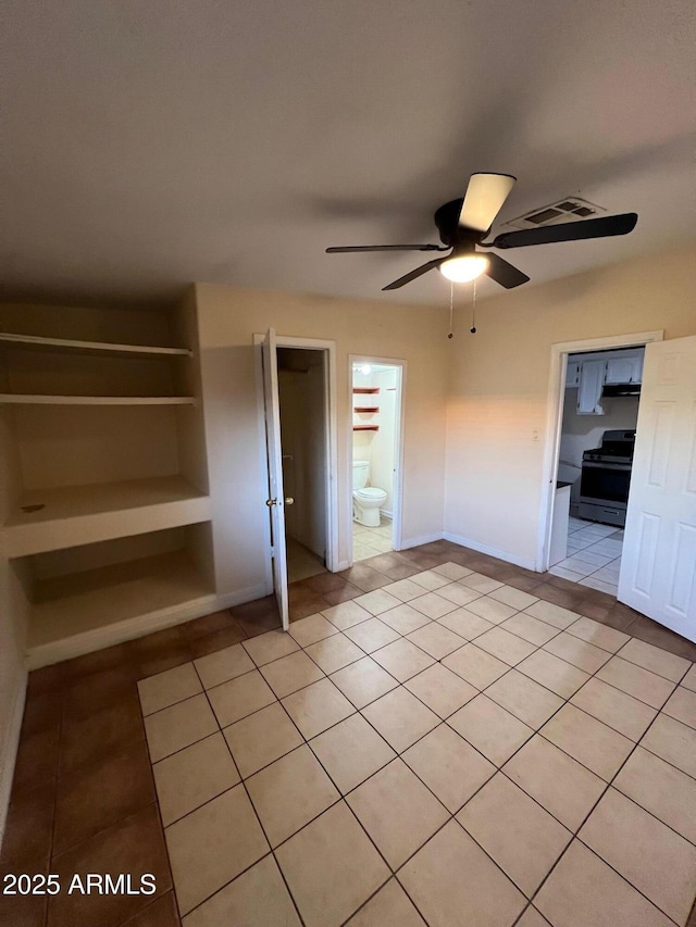 unfurnished bedroom with ceiling fan, light tile patterned floors, and ensuite bathroom