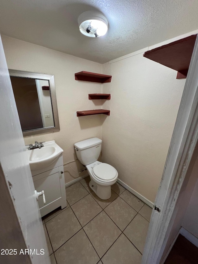 bathroom featuring a textured ceiling, toilet, vanity, and tile patterned flooring