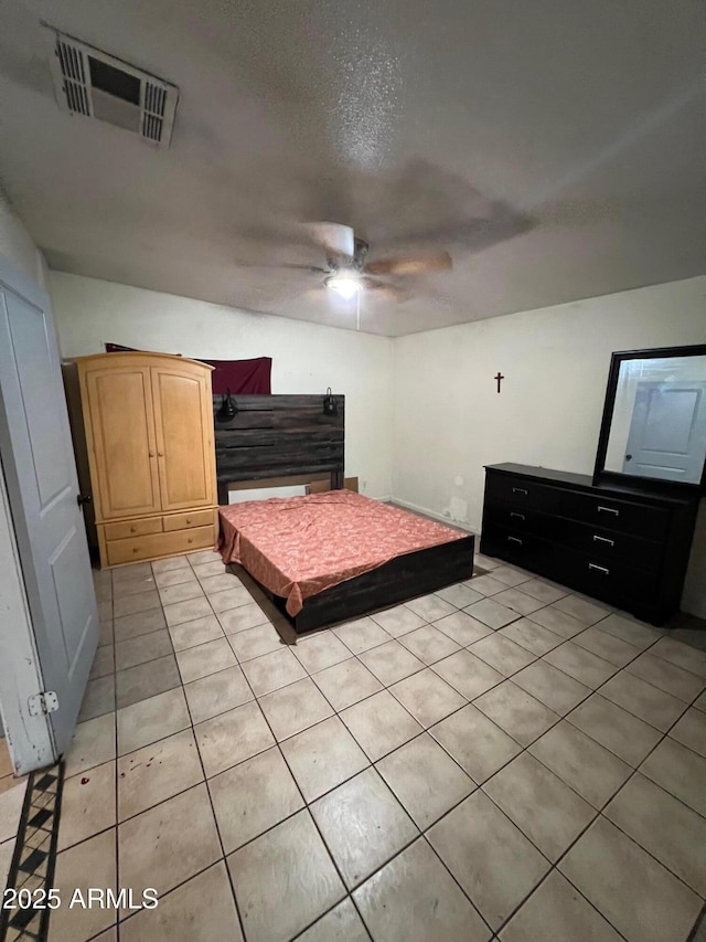 bedroom featuring a textured ceiling, ceiling fan, and light tile patterned floors