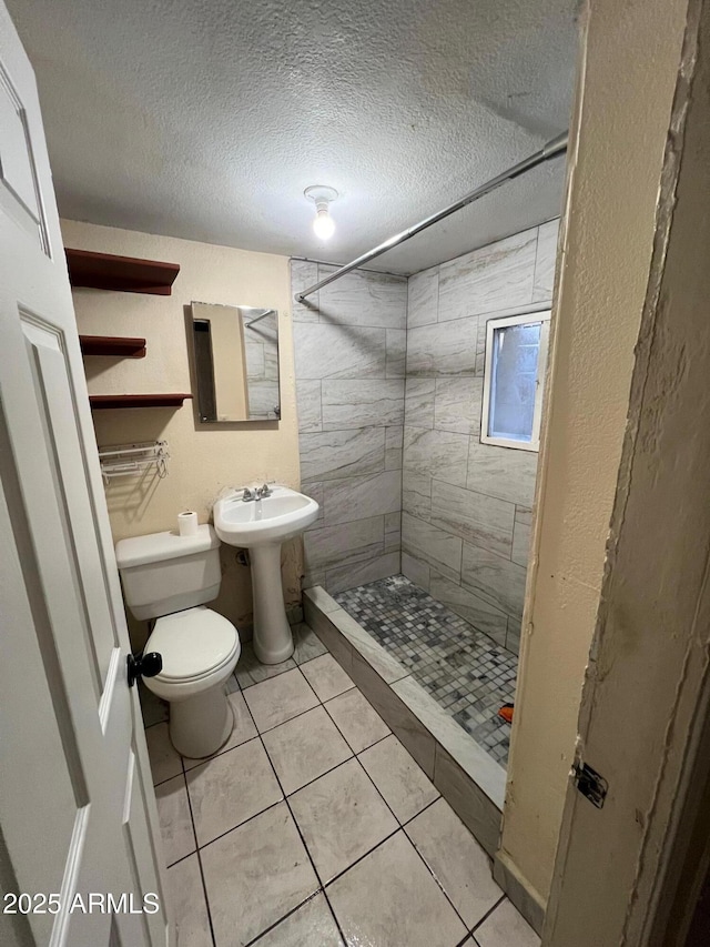 bathroom featuring a textured ceiling, tile patterned floors, sink, toilet, and tiled shower