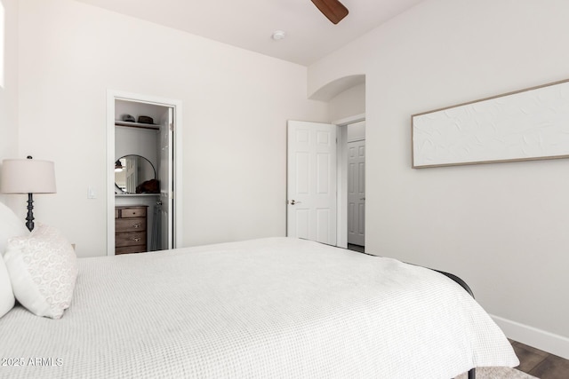 bedroom featuring a ceiling fan, wood finished floors, baseboards, a closet, and a spacious closet