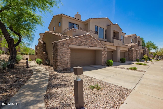 view of front of house featuring driveway, a tile roof, a balcony, an attached garage, and stucco siding