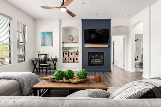 7445 E Eagle Crest Dr Unit 1145, Mesa, AZ 85207 - living room featuring wood finished floors, a fireplace, baseboards, ceiling fan, and arched walkways