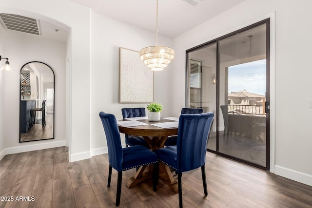 dining room featuring visible vents, arched walkways, wood finished floors, and a chandelier