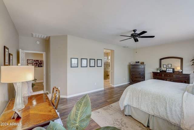 bedroom with connected bathroom, dark wood-type flooring, and ceiling fan