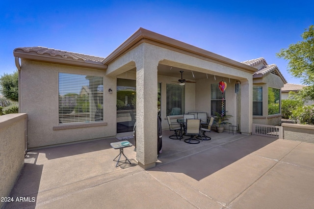 rear view of property with ceiling fan and a patio area