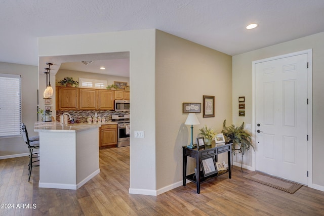 kitchen with decorative light fixtures, a breakfast bar area, backsplash, kitchen peninsula, and stainless steel appliances