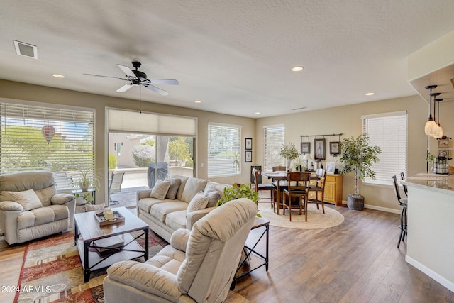 living room with ceiling fan, a textured ceiling, and dark hardwood / wood-style flooring