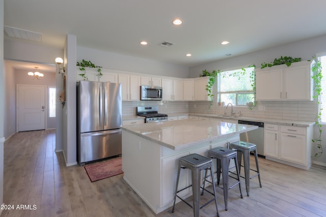 kitchen with stainless steel appliances, a center island, and light wood-type flooring