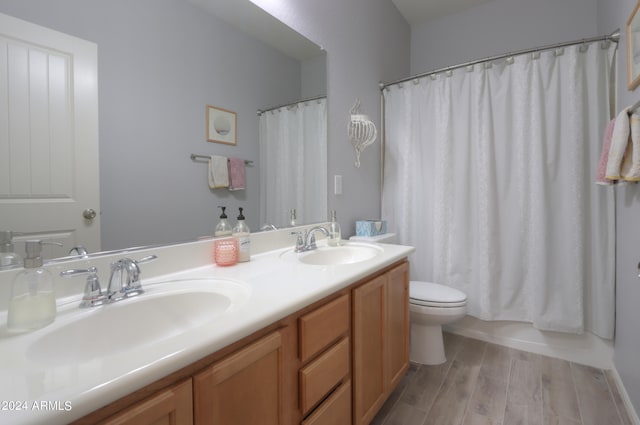 bathroom with dual sinks, toilet, oversized vanity, and hardwood / wood-style floors