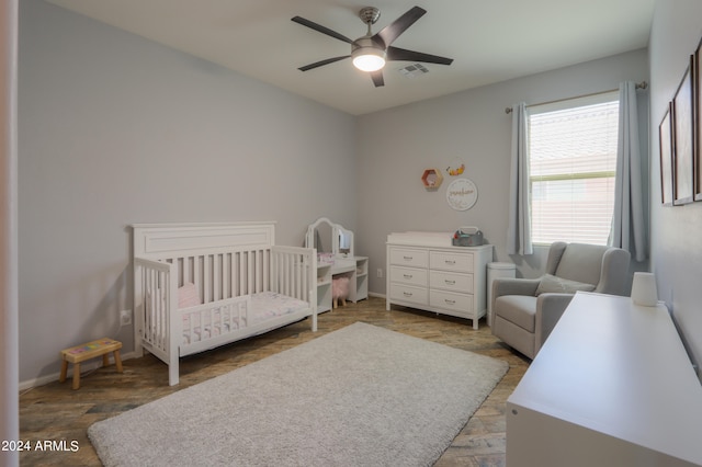 bedroom with ceiling fan and a nursery area