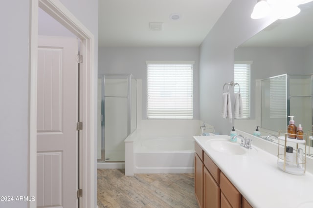 bathroom with plus walk in shower, vanity with extensive cabinet space, and hardwood / wood-style flooring