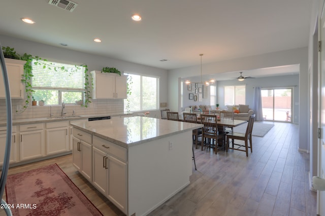 kitchen featuring a kitchen island, a wealth of natural light, sink, and white cabinetry