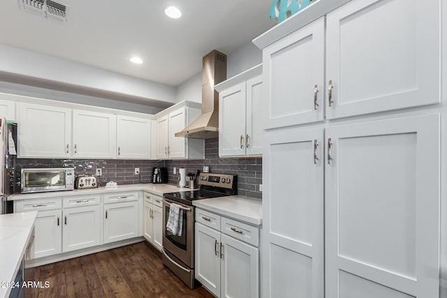 kitchen featuring appliances with stainless steel finishes, dark hardwood / wood-style floors, white cabinetry, and wall chimney range hood