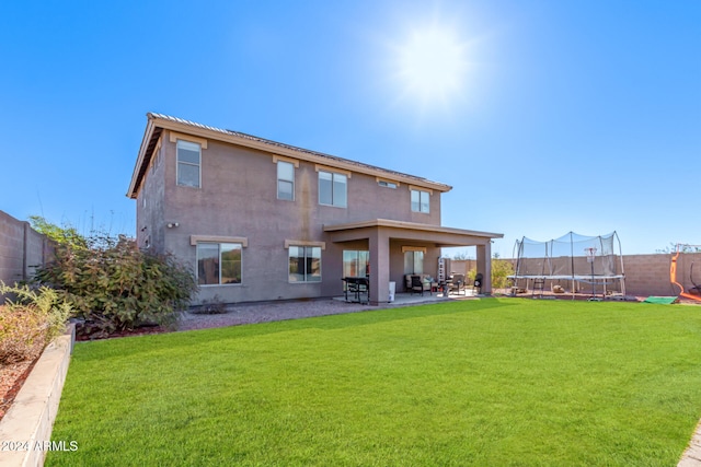 back of house with a yard, a patio, and a trampoline