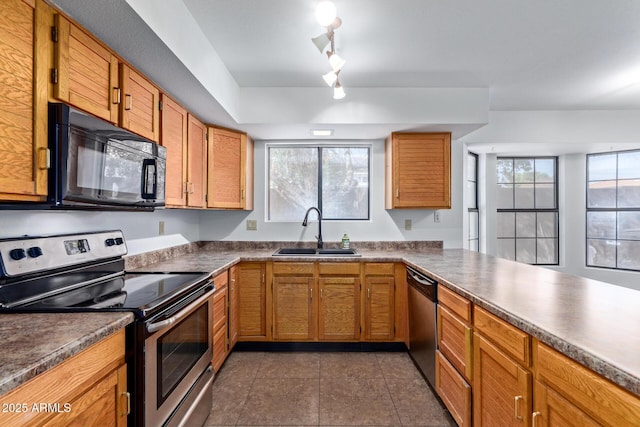 kitchen featuring stainless steel appliances, a healthy amount of sunlight, sink, and dark tile patterned flooring