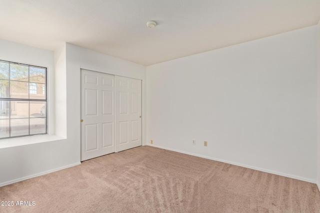 unfurnished bedroom with light colored carpet and a closet