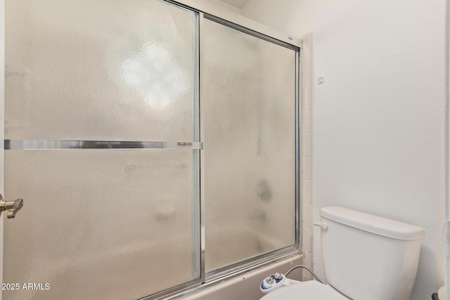 bathroom featuring toilet and combined bath / shower with glass door