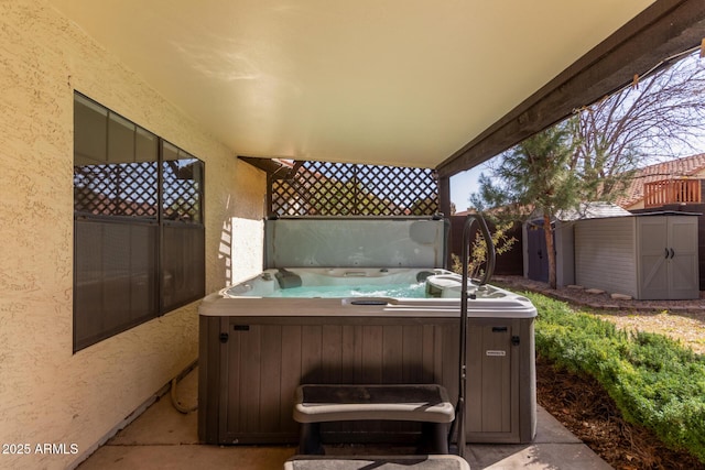 view of patio / terrace featuring a hot tub and a storage unit