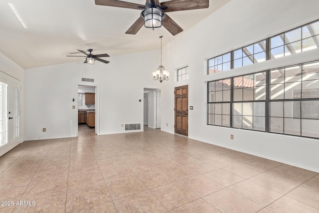 unfurnished living room featuring light tile patterned floors, ceiling fan with notable chandelier, high vaulted ceiling, and a healthy amount of sunlight